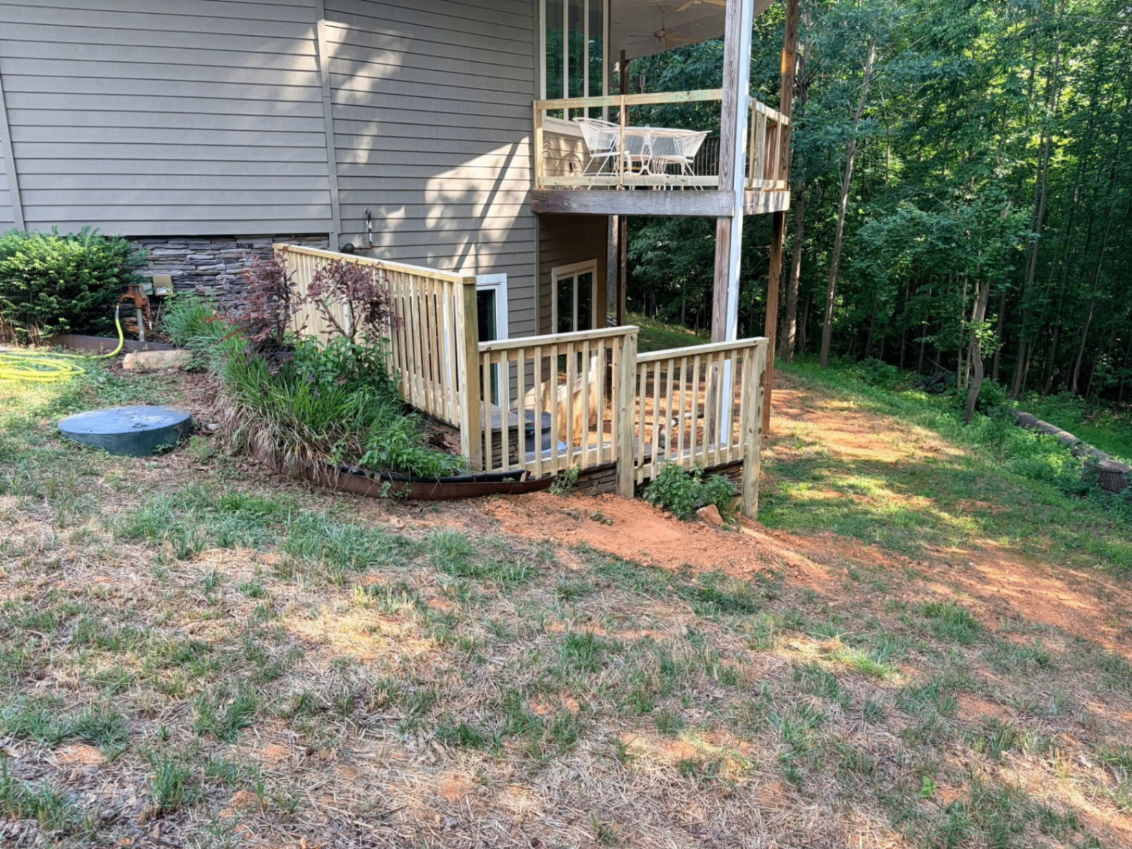 Compact ground-level deck with privacy screen tucked beside a hillside home