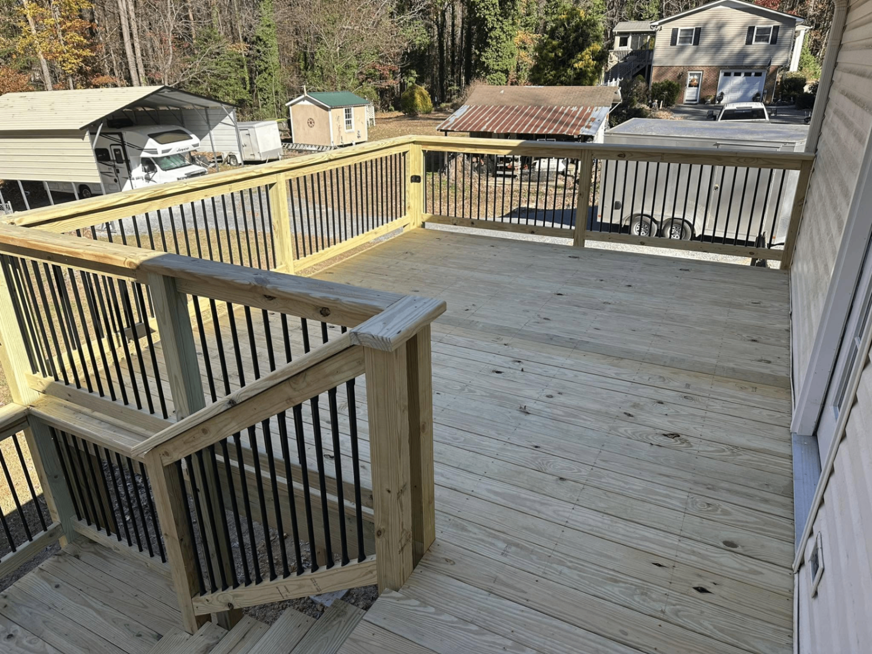 Newly built pressure-treated wood deck with black metal balusters and staircase